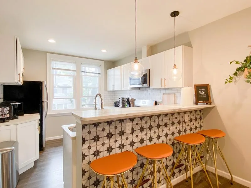 Kitchen — star-pattern tile island, glass globe pendants, gold + orange barstools