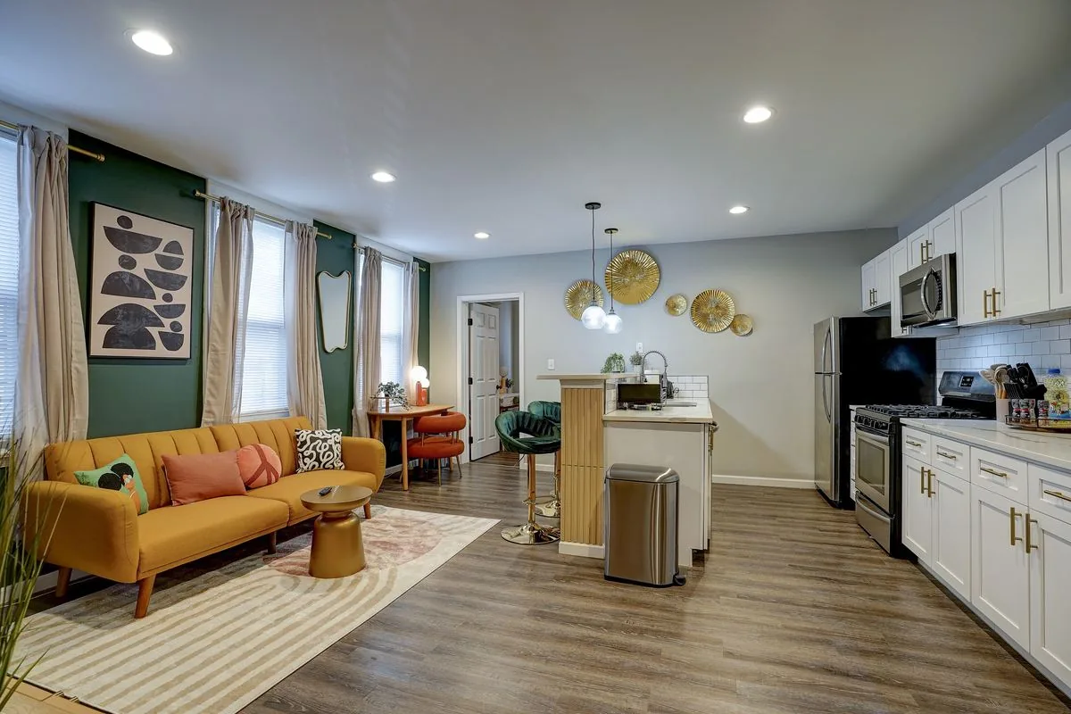Retro Revive open-plan living room with mustard sofa, forest green accent wall and kitchen bar
