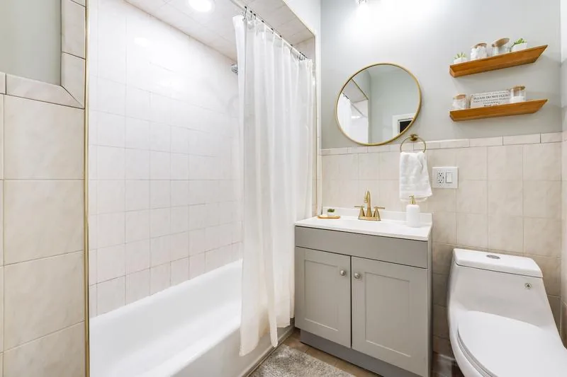 Spa-style bathroom with gold fixtures and round mirror